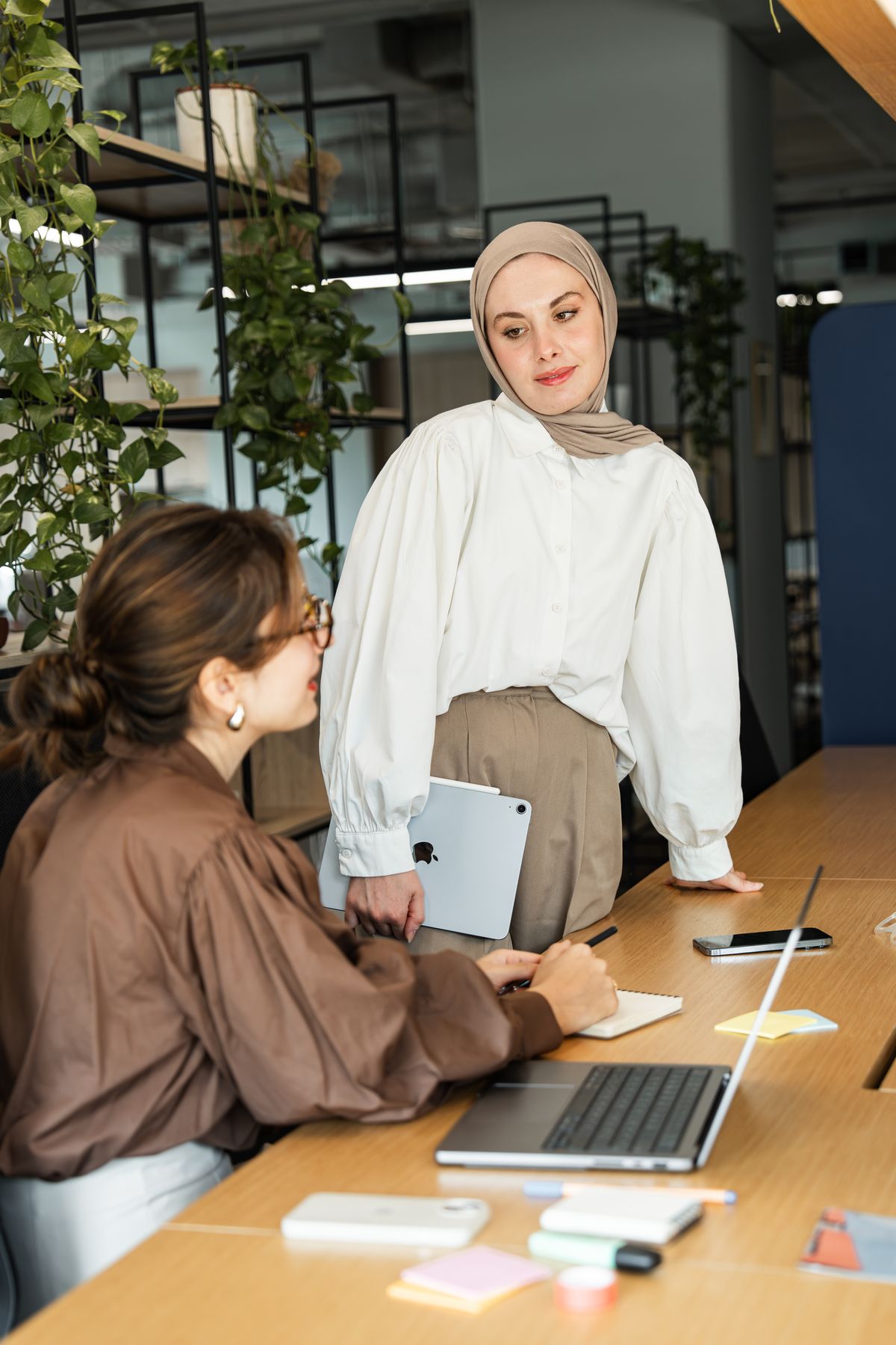 Twee collega's overleggen aan een bureau in een licht kantoor