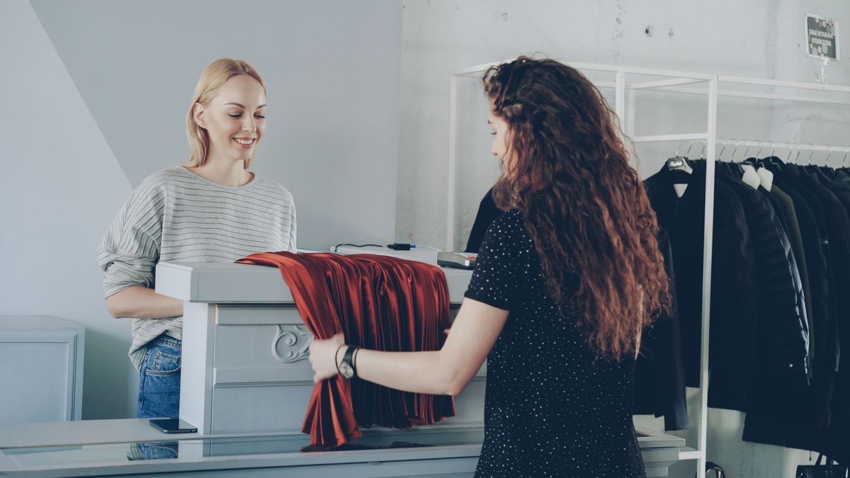 Winkelmedewerker helpt een klant aan de kassa van een kledingzaak