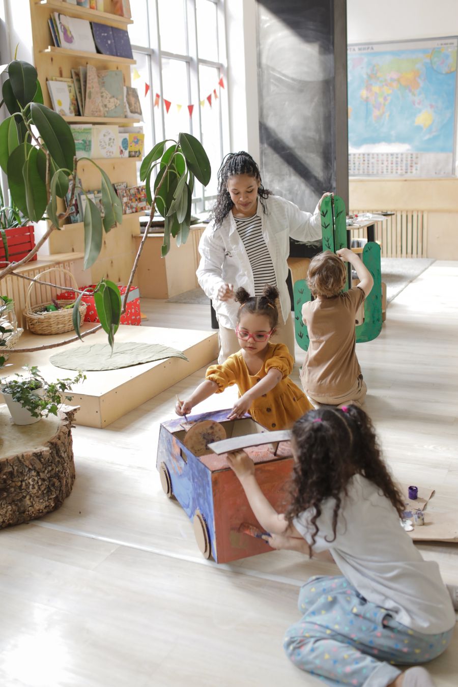Pedagogisch medewerker met kinderen die samen knutselen op de groep